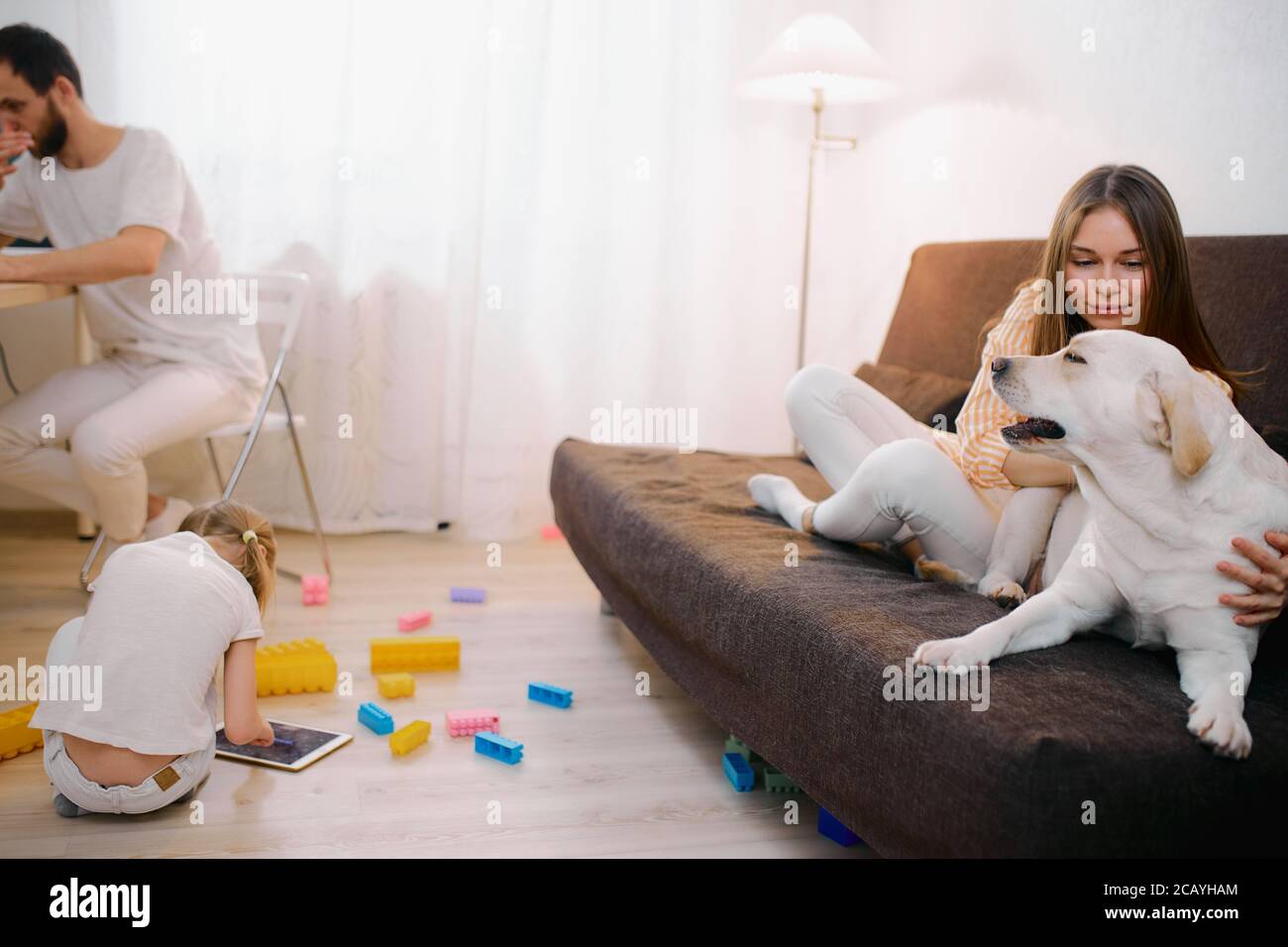 la famille adorable se composait de mère, père et petite fille à la maison  dans la salle de séjour, dans des vêtements blancs décontractés. les  enfants jouant sur le sol, tandis que