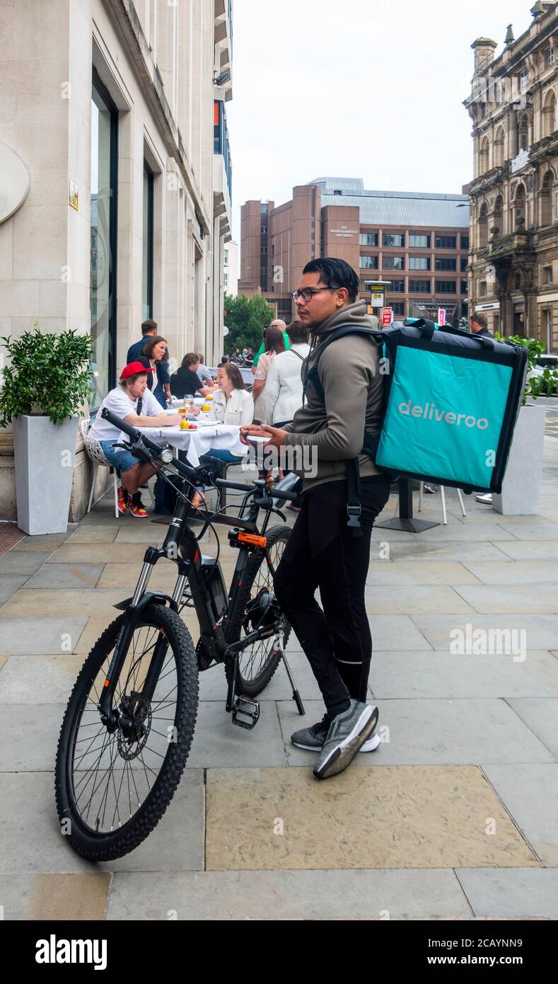 Jeune homme avec vélo en attente d'une commande de nourriture deliveroo Dans un bistro de Castle Street à Liverpool Banque D'Images