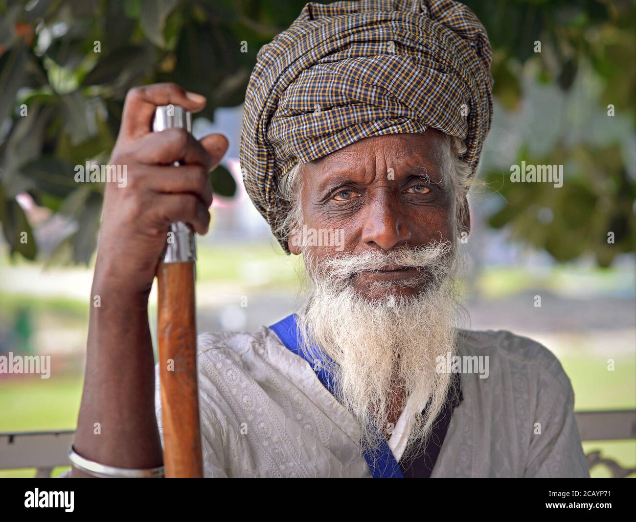 Le vieux dévot de Sikh indien avec des yeux de sang repose sur son bâton de marche et regarde dans la caméra. Banque D'Images