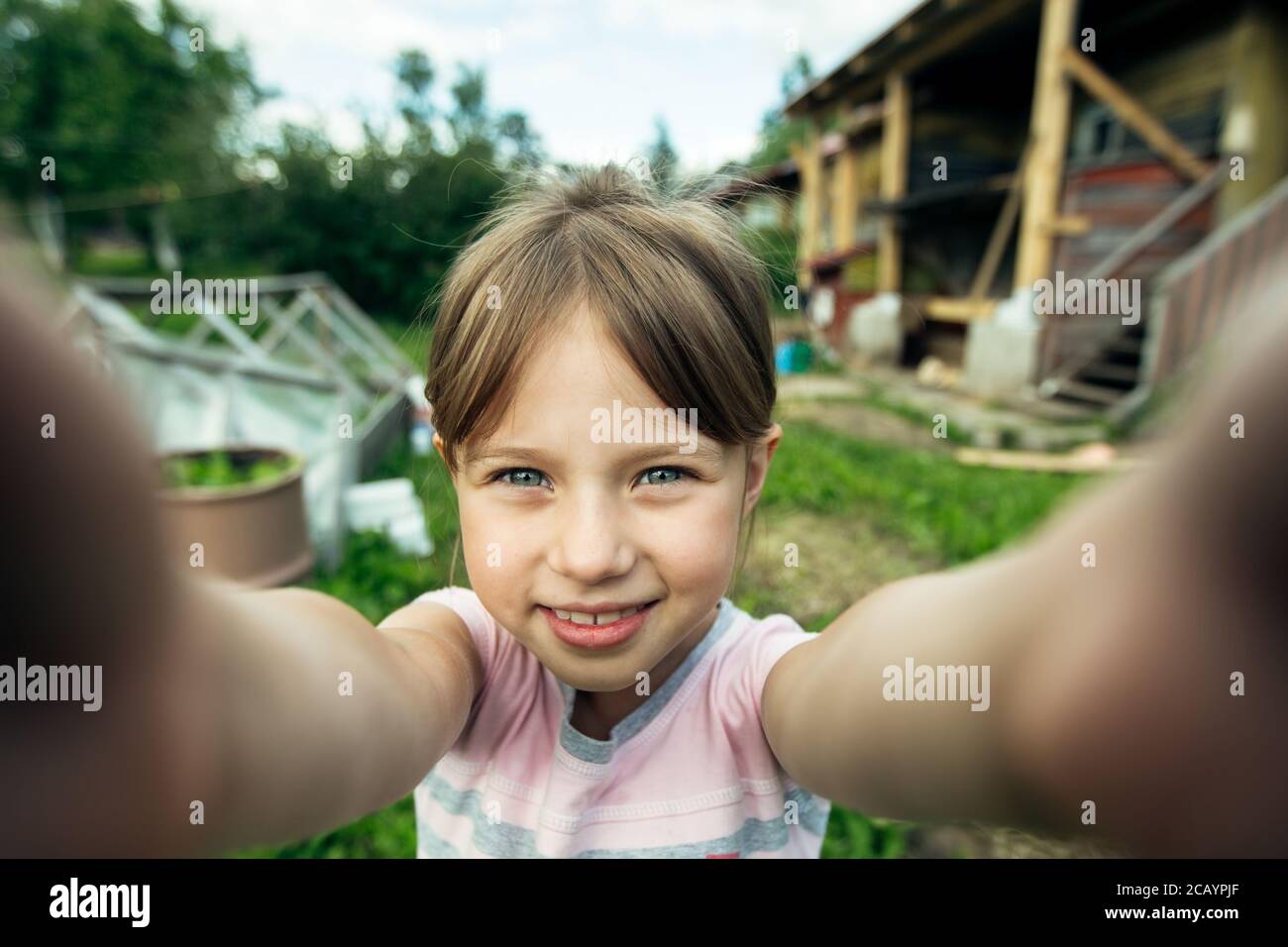 Petite fille mignonne drôle prenant un selfie dehors dans la maison de vilage. Banque D'Images