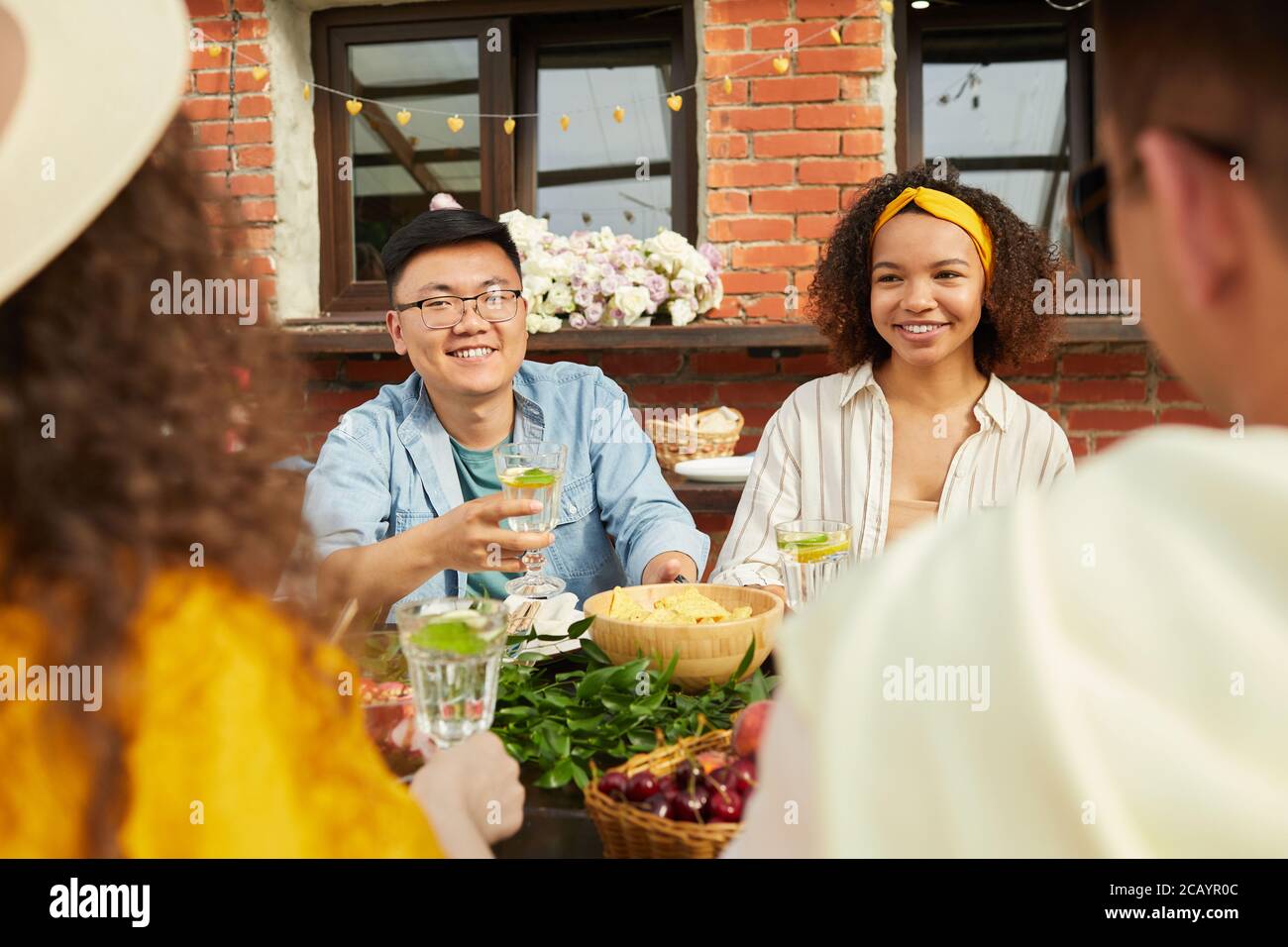 Groupe multiethnique d'amis qui dînent ensemble à l'extérieur tout en étant assis à table sur la terrasse ouverte, espace de copie Banque D'Images