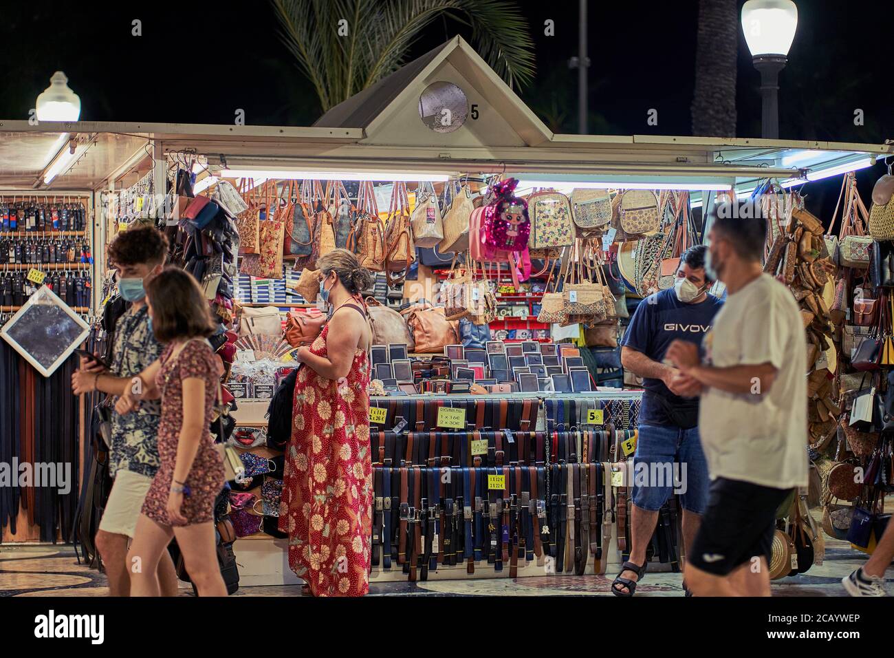 Les clients parcourent les ceintures et sacs en cuir à vendre dans un stand du marché de la promenade à Alicante, Espagne, Europe, juillet 2020 Banque D'Images Les clients parcourent les ceintures et sacs en cuir à vendre dans un stand du marché de la promenade à Alicante, Espagne, Europe, juillet 2020 Banque D'Images