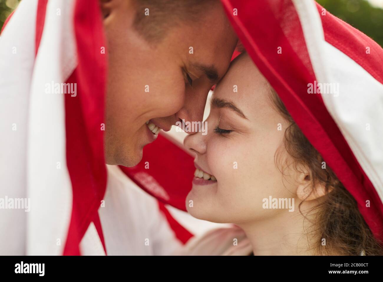 Vue de côté d'un jeune couple affectueux et souriant couvert d'un drapeau américain Banque D'Images