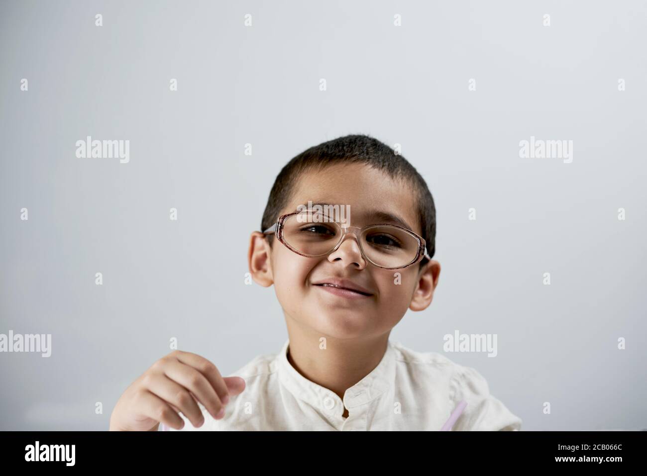 Portrait d'un garçon de race mixte de 7 ans gai sur fond blanc. Un portrait élégant de garçon d'école Banque D'Images