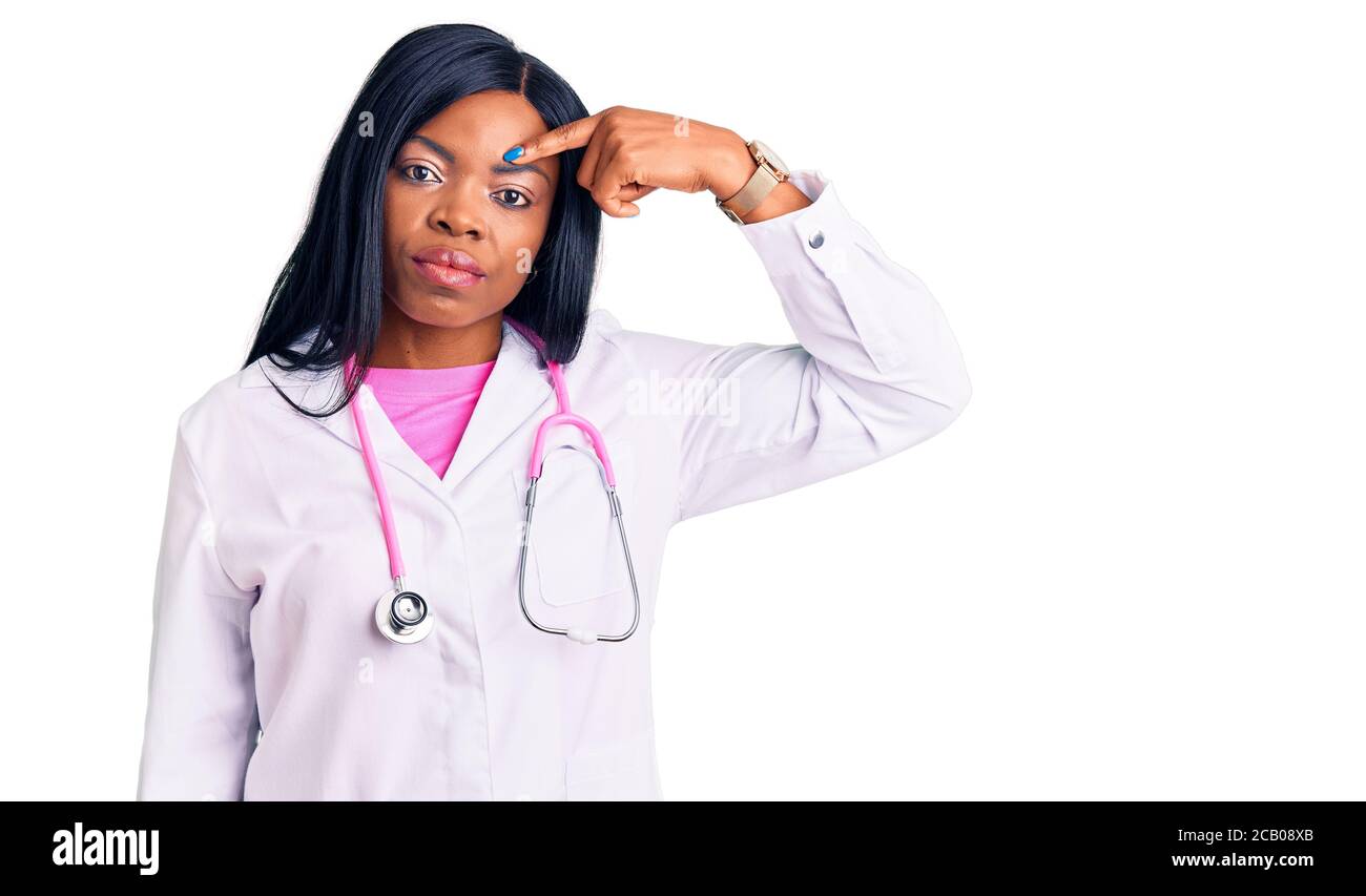Jeune afro-américaine femme portant le docteur stéthoscope pointant malheureux à pipple sur le front, infection laid de la tête noire. Acné et problème de peau Banque D'Images