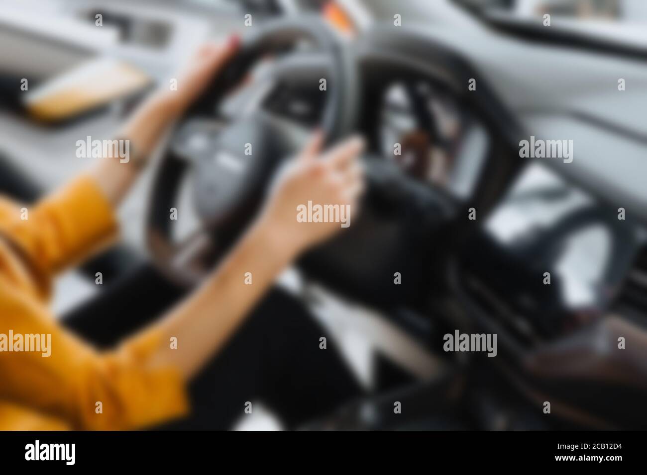 Résumé flou des mains femelles sur le volant d'une voiture pendant la conduite. Banque D'Images