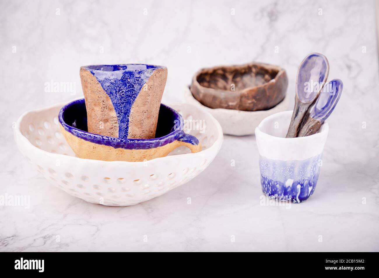 Décor en céramique sur fond de marbre blanc. Blanc, bleu et marron. Tasses, cuillères, bols. Fait à la main Banque D'Images Décor en céramique sur fond de marbre blanc. Blanc, bleu et marron. Tasses, cuillères, bols. Fait à la main Banque D'Images