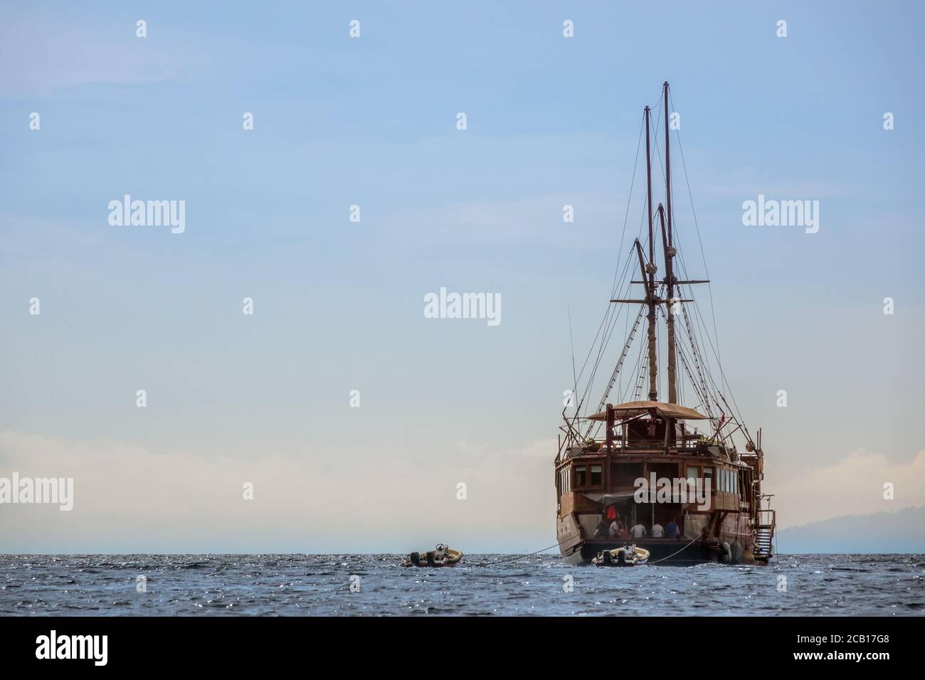 Grand voilier avec plongeurs plongées dans l'océan. Deux bateaux à moteur gonflables sur une laisse Banque D'Images