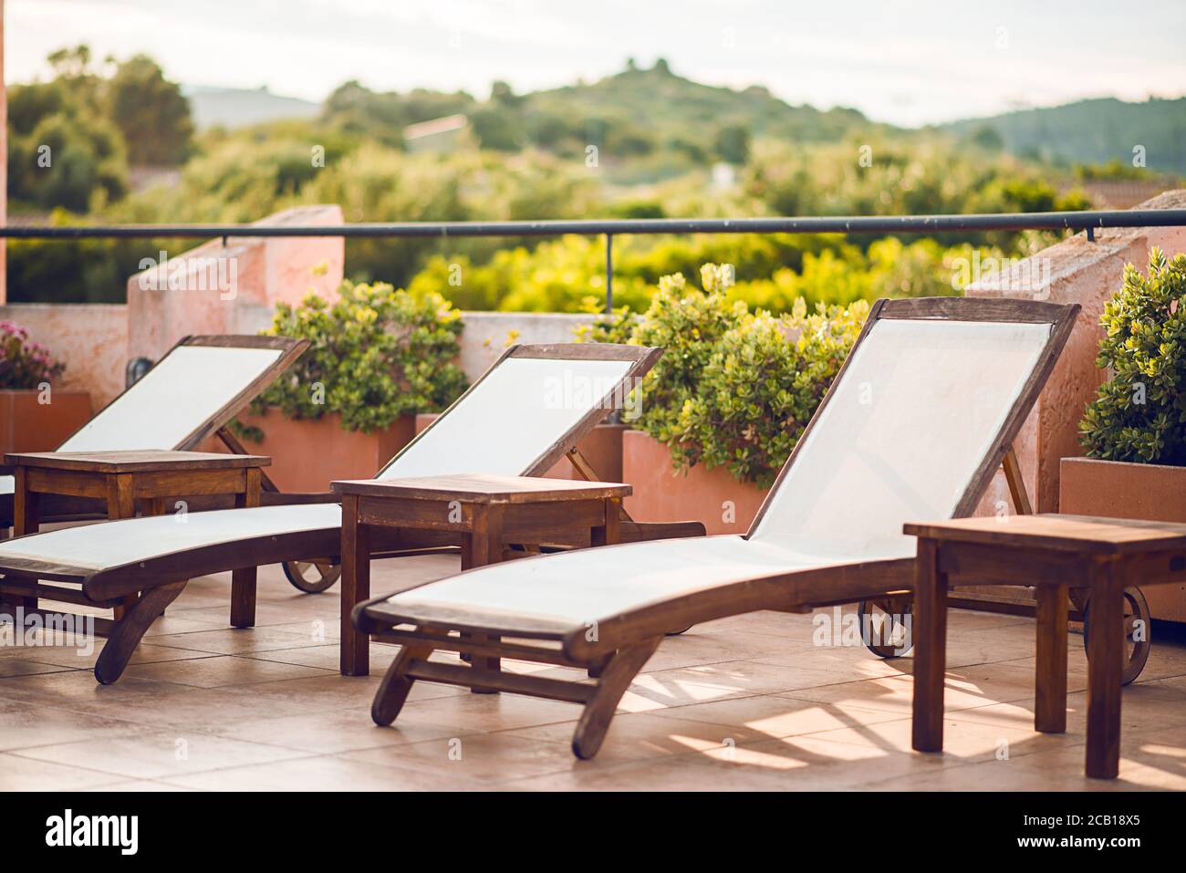 Chaises longues en bois vierges dans une rangée de l'hôtel de luxe. Solarium pour bains de soleil. Banque D'Images