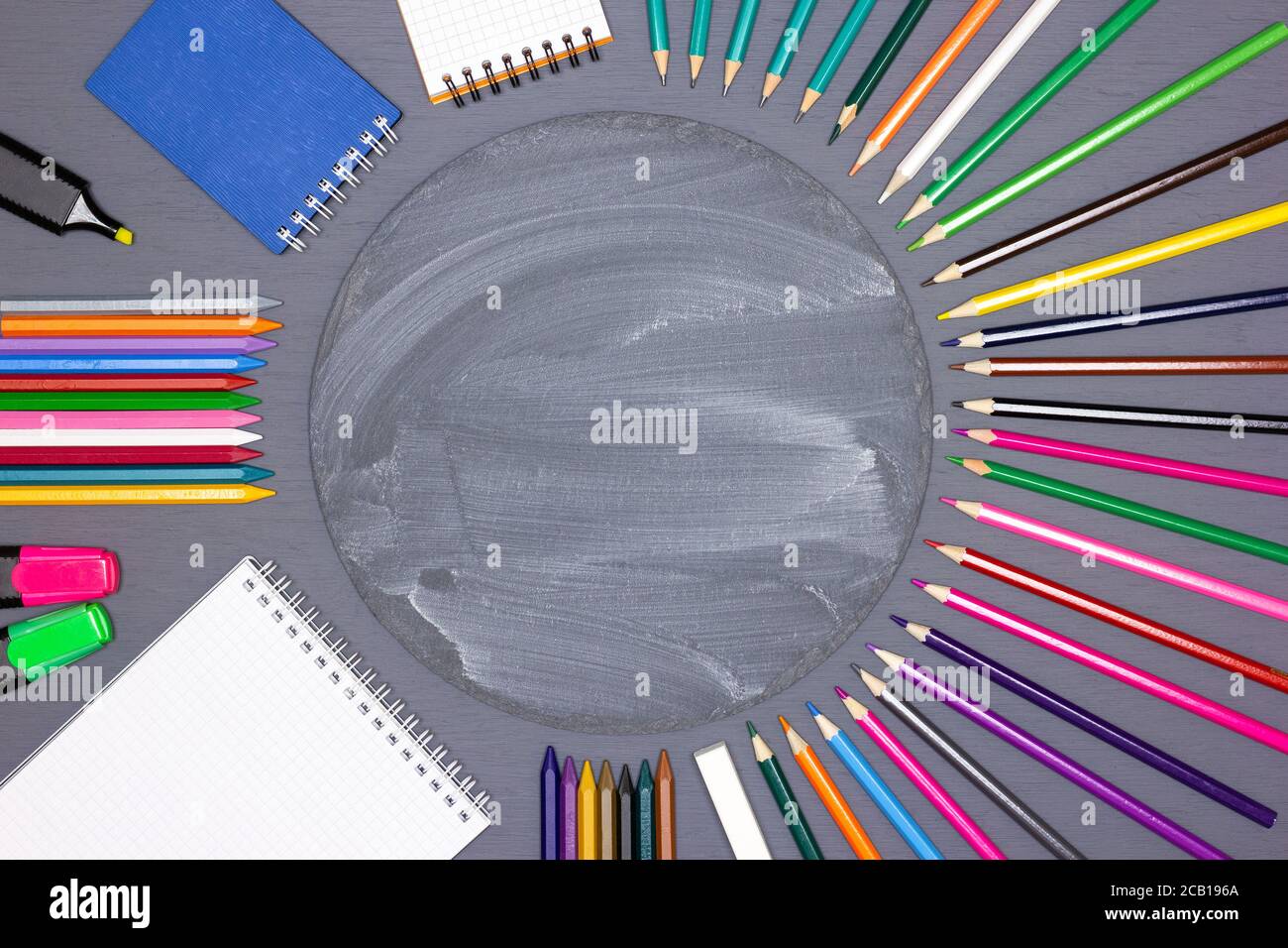 Carnets vierges, marqueurs, crayons de couleur, bâton de craie avec tableau rond sur le bureau. Créativité des enfants, retour à l'école concept fond Banque D'Images