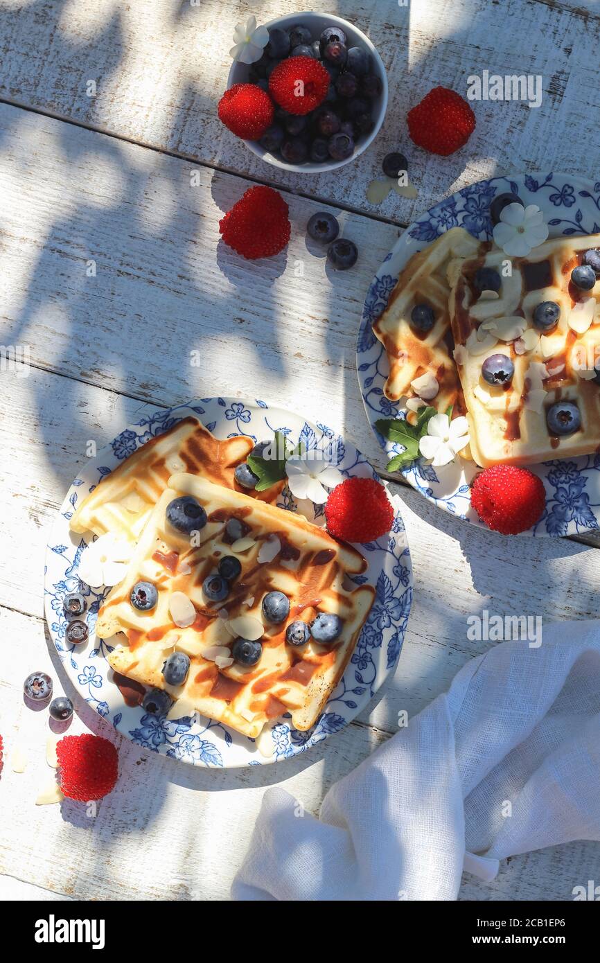Table de petit déjeuner le week-end - gaufres avec baies d'été sous la dure léger Banque D'Images