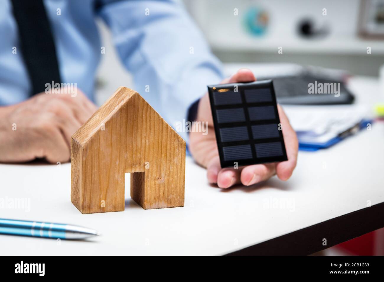 Homme d'affaires avec une maison et un panneau solaire dans le bureau, concept énergie verte et économie Banque D'Images