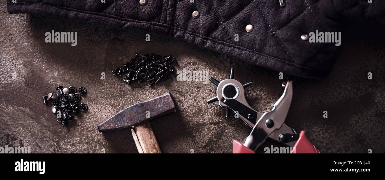 panorama avec beaucoup d'outils comme une pince à poinçonner en cuir ou un marteau et quelques rivets en cuivre, la fabrication d'équipement de maroquinerie sur un backgound brun Banque D'Images