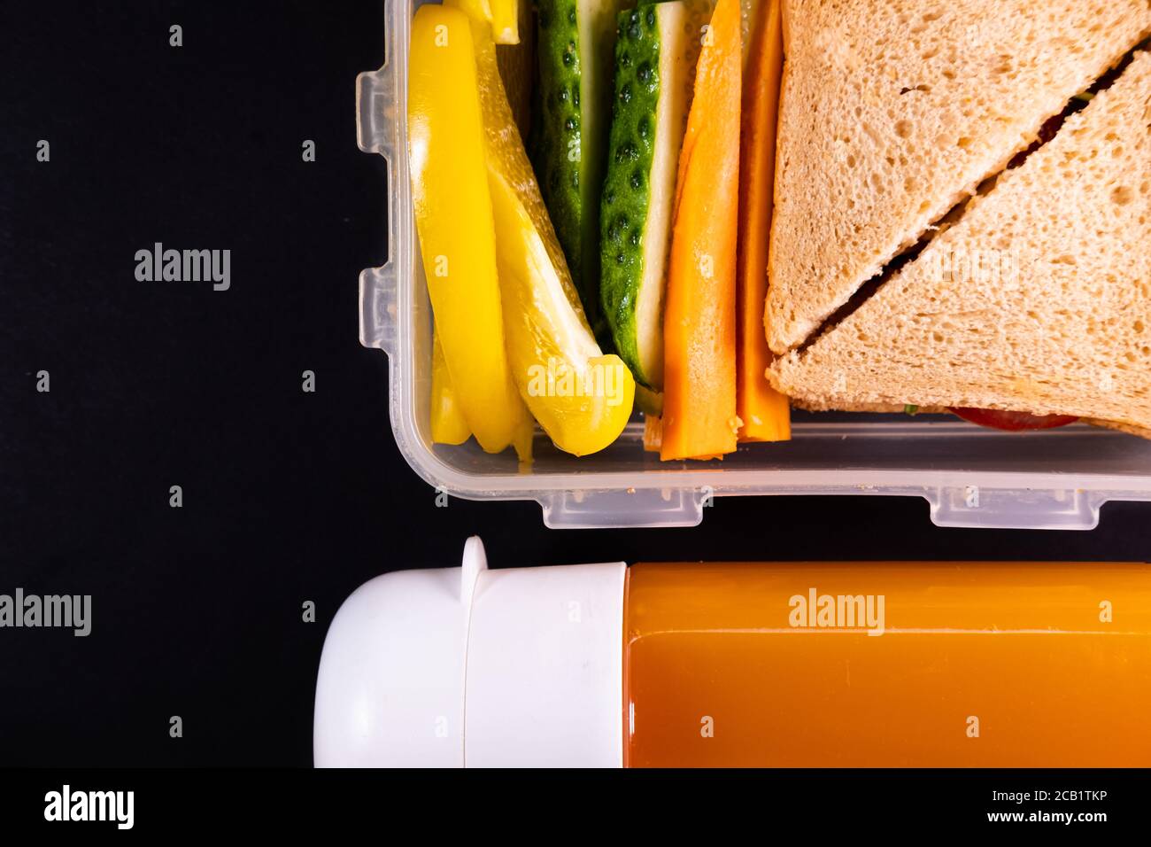 Sandwich au pain et légumes dans une boîte à lunch à côté d'une bouteille de jus - vue du dessus et espace de copie. Déjeuner sain, repas à base de plantes ou repas végétarien Banque D'Images