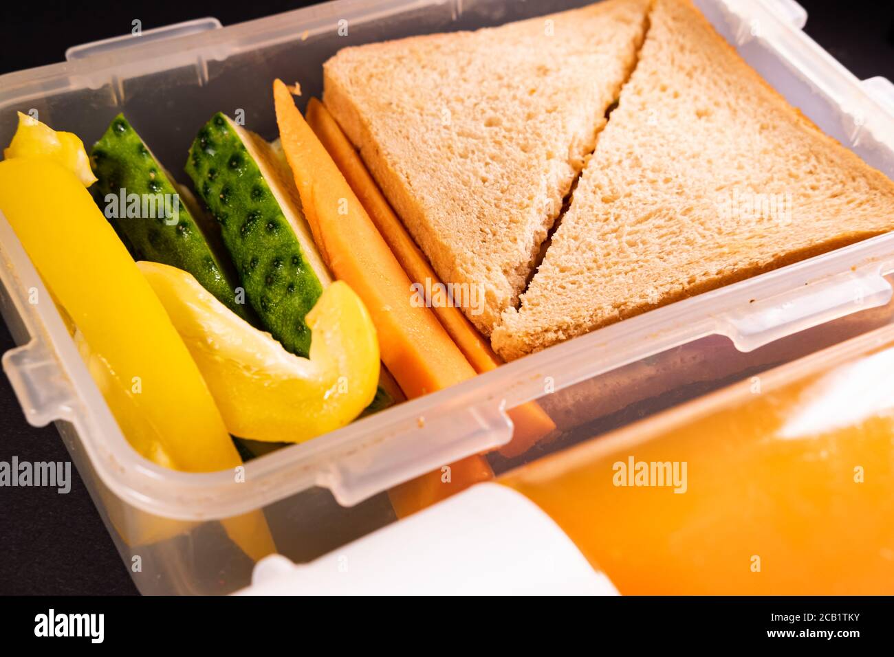 Sandwich au pain et légumes dans une boîte à lunch à côté d'une bouteille de jus. Déjeuner sain, déjeuner à base de plantes ou déjeuner scolaire végétarien Banque D'Images