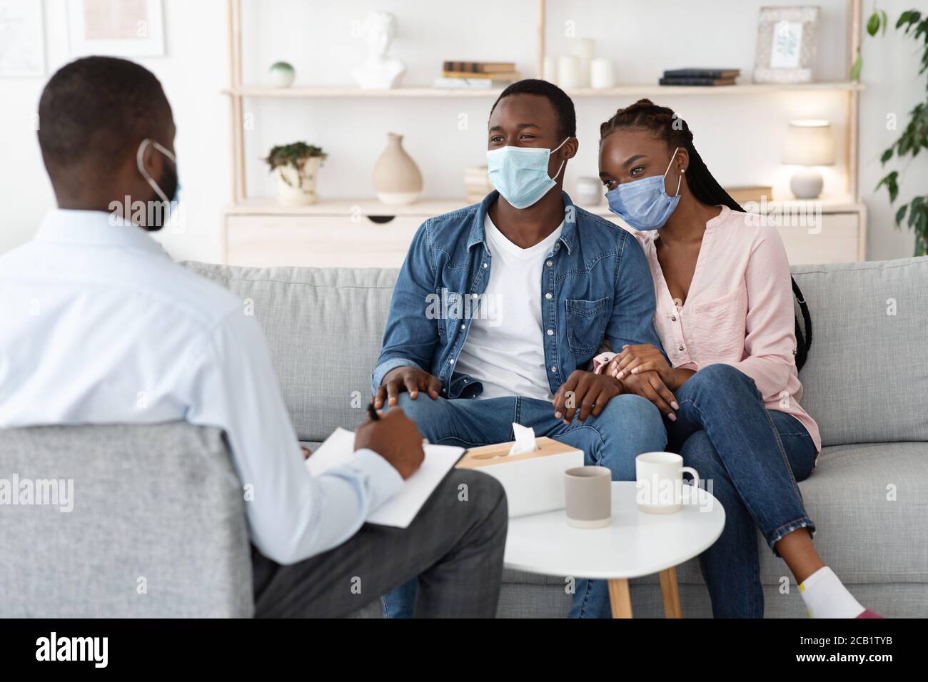 Thérapie familiale pendant une pandémie. Couple noir en masques de protection au bureau du conseiller Banque D'Images