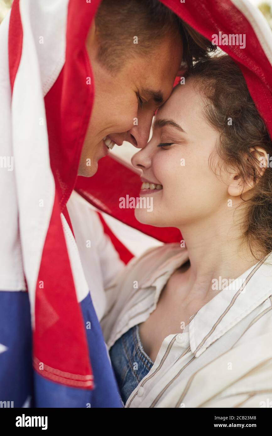 Portrait en gros plan d'un jeune couple affectueux et souriant recouvert d'un drapeau américain Banque D'Images