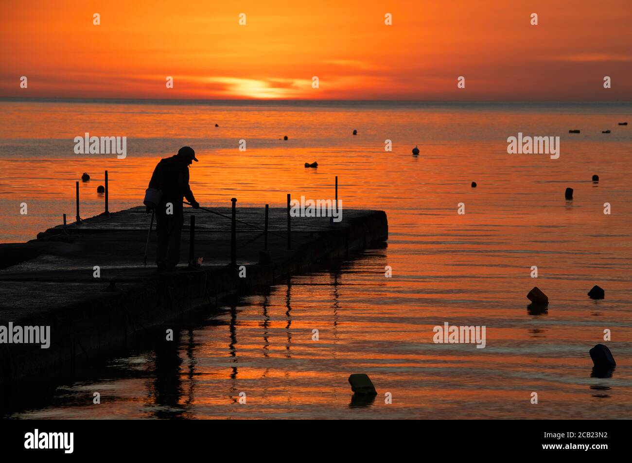 silhouette de pêcheur près de la mer au lever du soleil. Routine quotidienne de pêcheur. Lever du soleil à Marsascala, Malte Banque D'Images