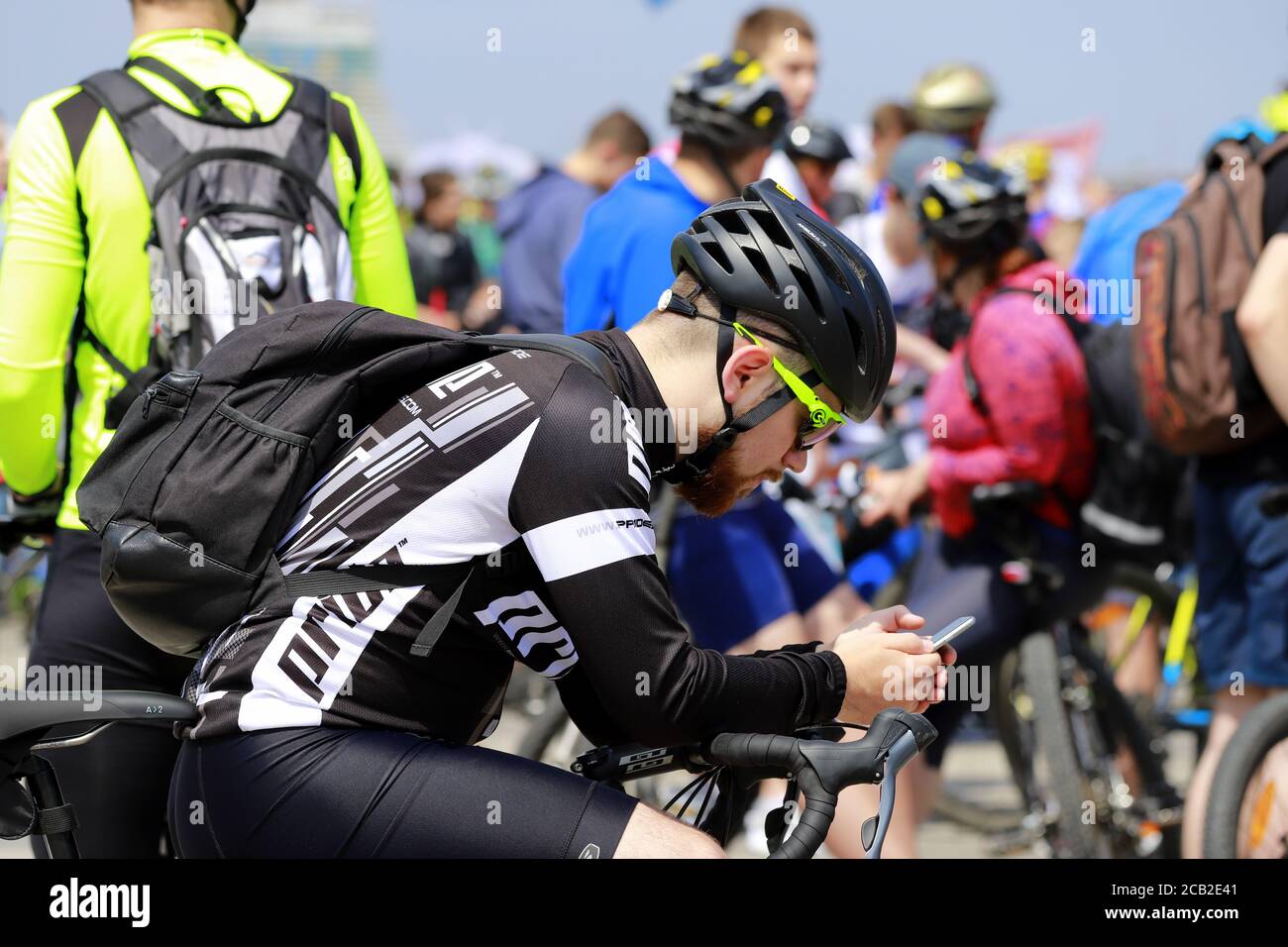 Ville de Dnipro, Ukraine 26 05 2019. Un jeune homme s'assoit dans un casque sur un vélo et regarde dans un smartphone. Cyclisme, événement sportif à Dnepr. Banque D'Images