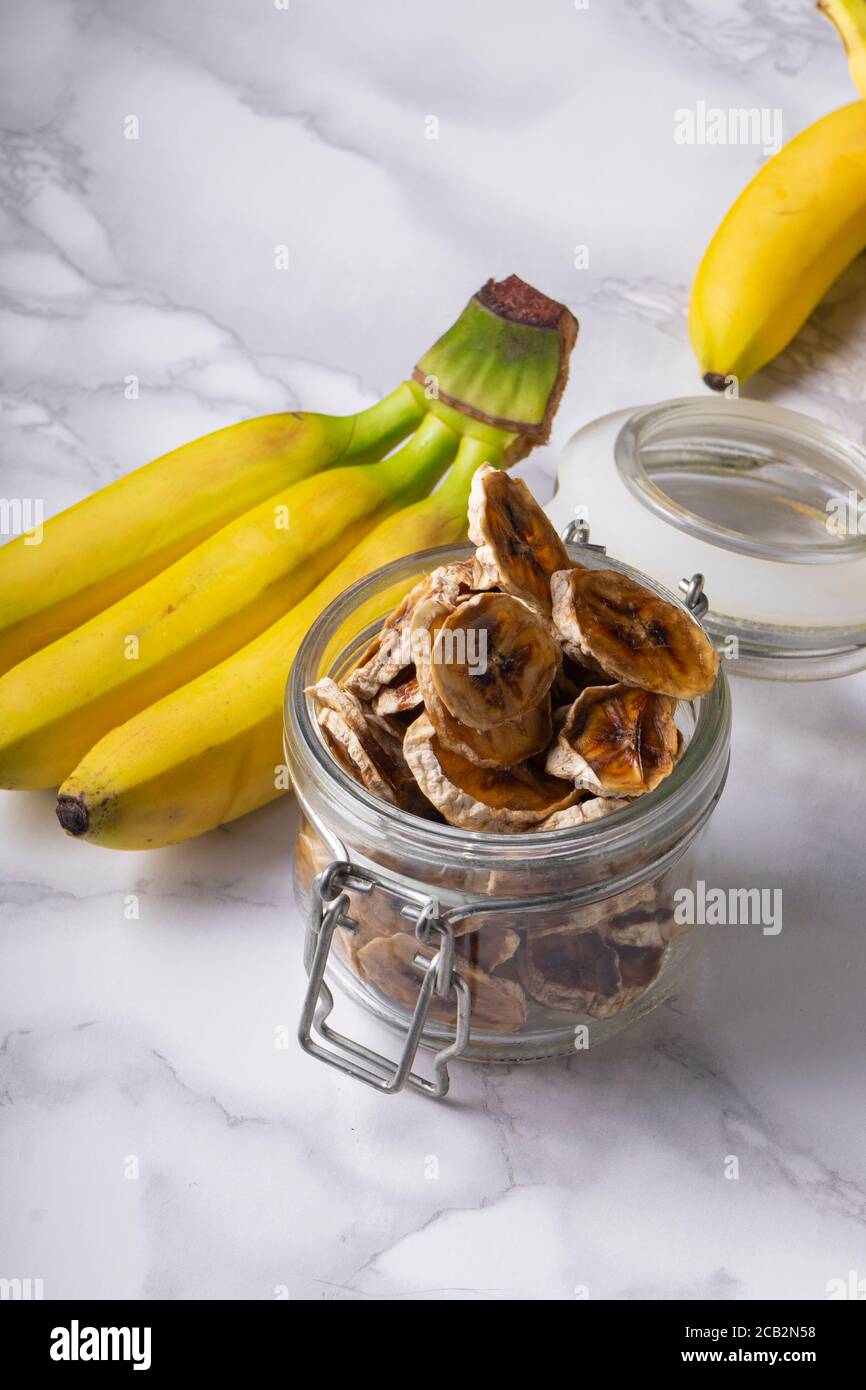 foyer sélectif, en-cas sain, tranches de banane séchées sur fond clair avec des fruits mûrs de banane Banque D'Images