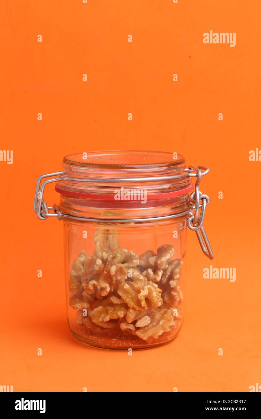 Gros plan vertical d'un pot de noix fissurées à l'intérieur un arrière-plan orange Banque D'Images