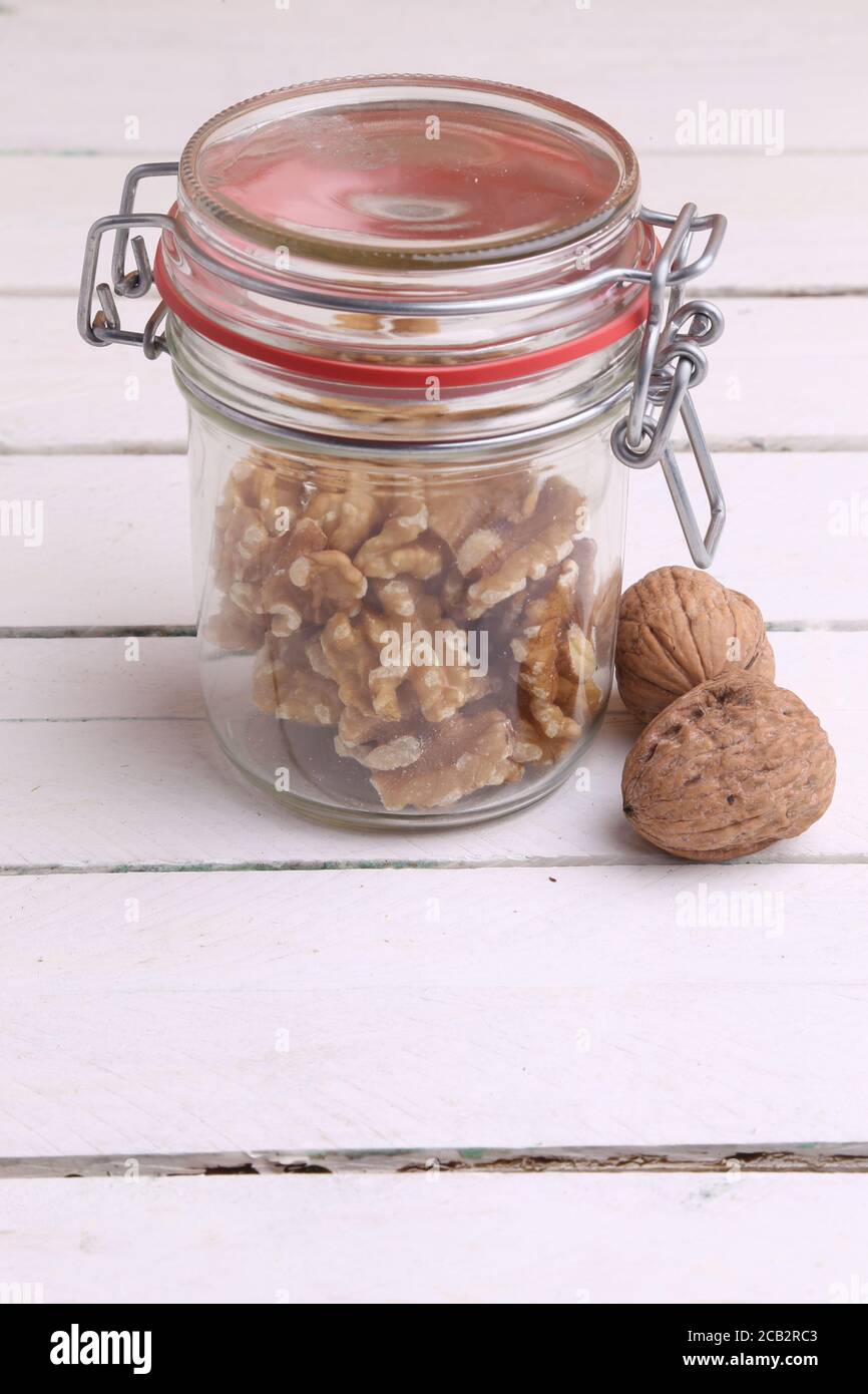Gros plan vertical d'un pot de noix fissurées à l'intérieur avec noix entières sur le côté Banque D'Images