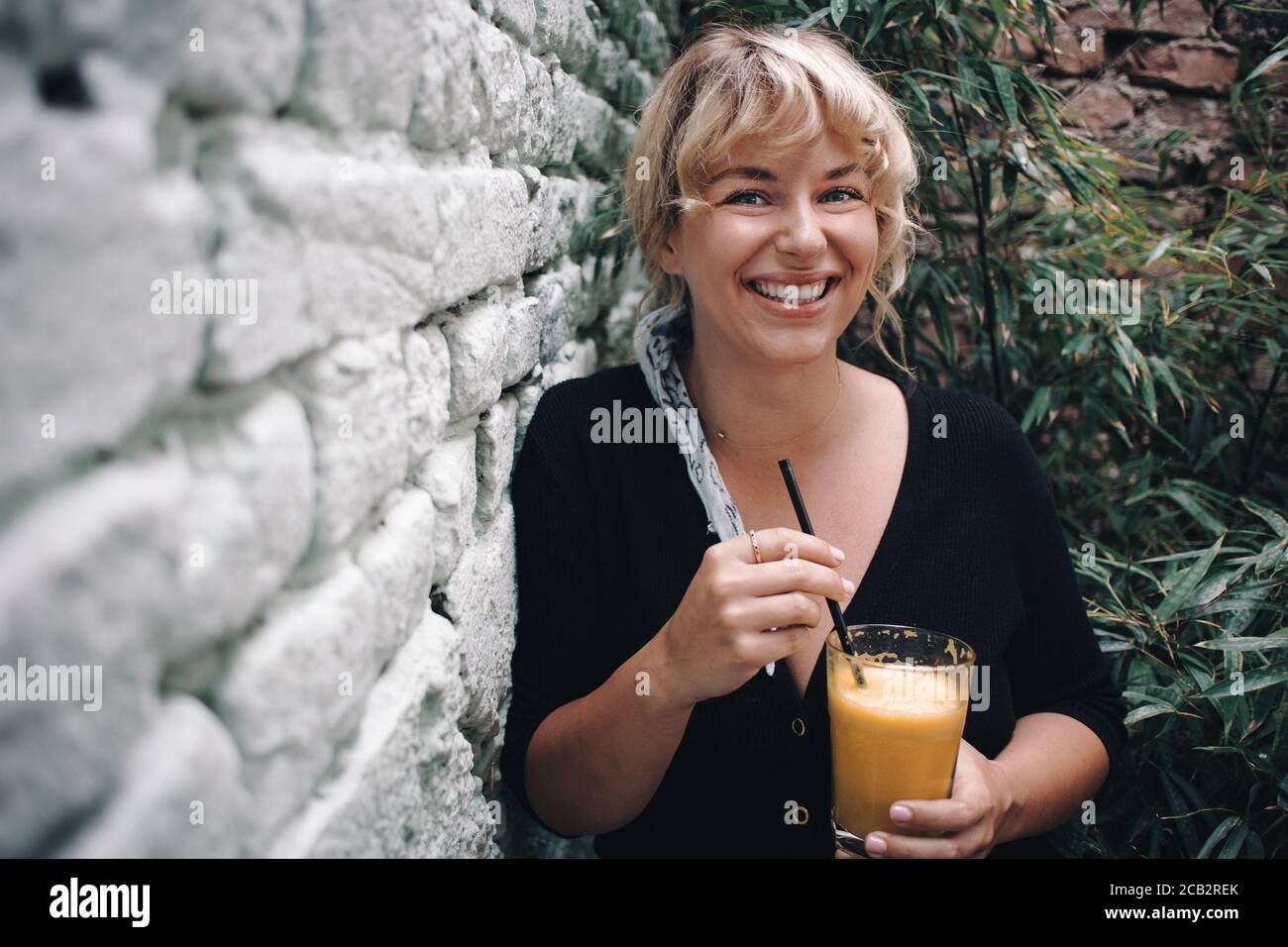 Belle jeune femme buvant du jus d'orange dans son jardin Banque D'Images