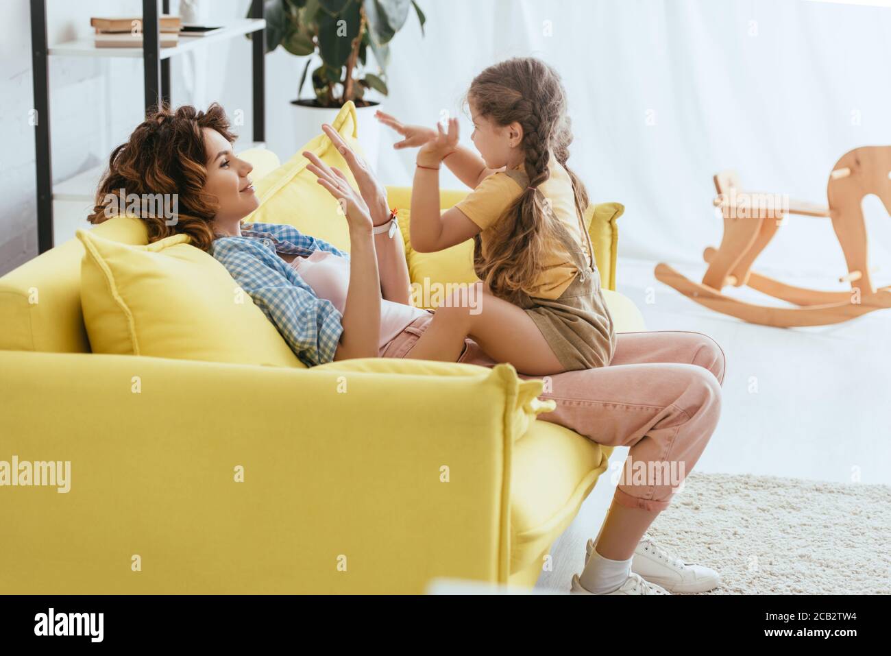 joyeux baby-sitter et enfant jouant au jeu de pat-a-gâteau tout en s'amusant sur le canapé Banque D'Images