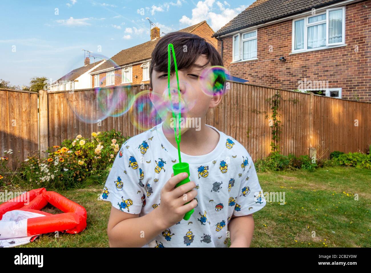 Un jeune garçon souffle de la bulle dans son jardin arrière. Banque D'Images