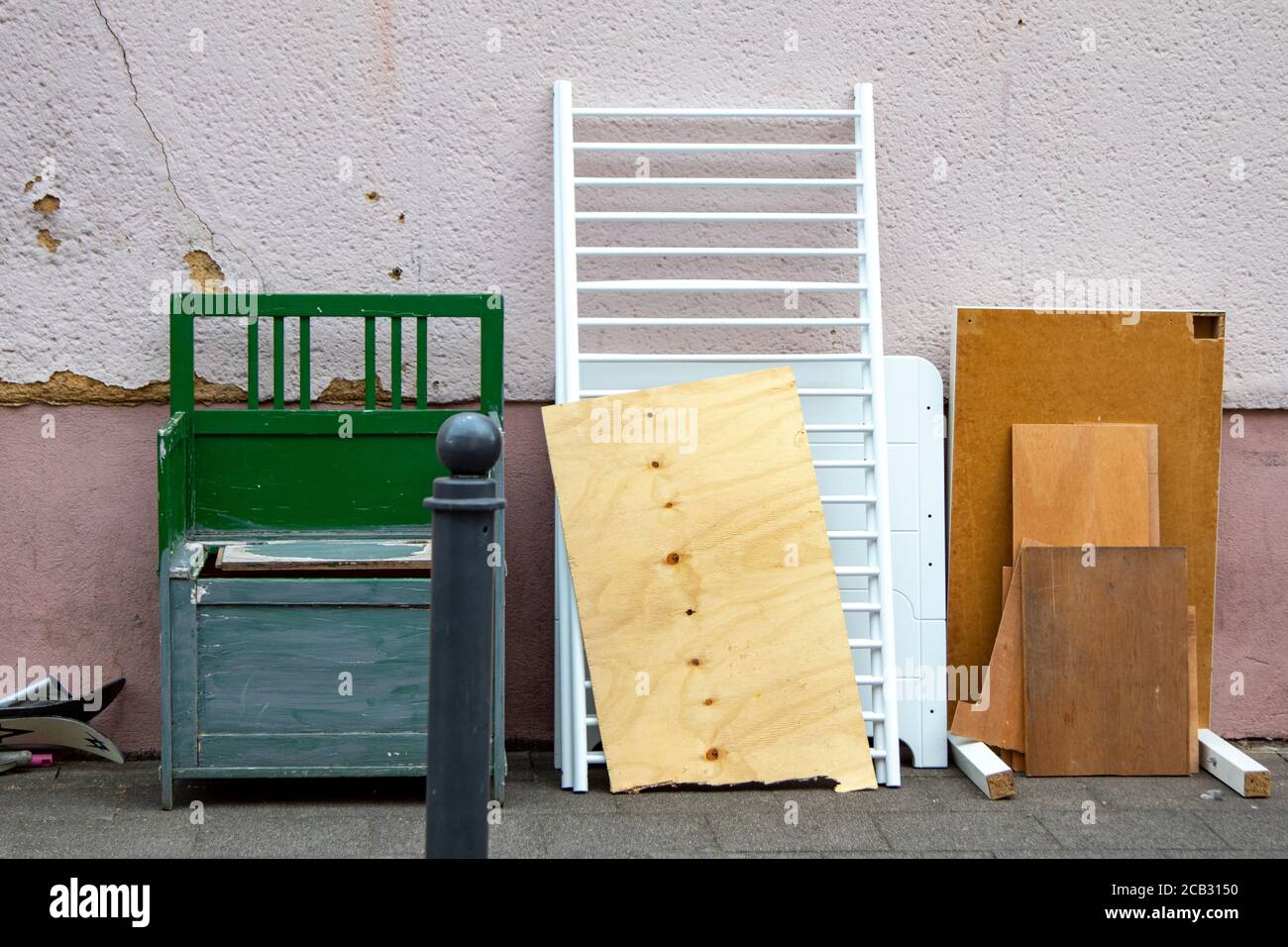 Déchets encombrants avec un vieux banc en bois, des planches et un lit bébé, mur comme arrière-plan Banque D'Images