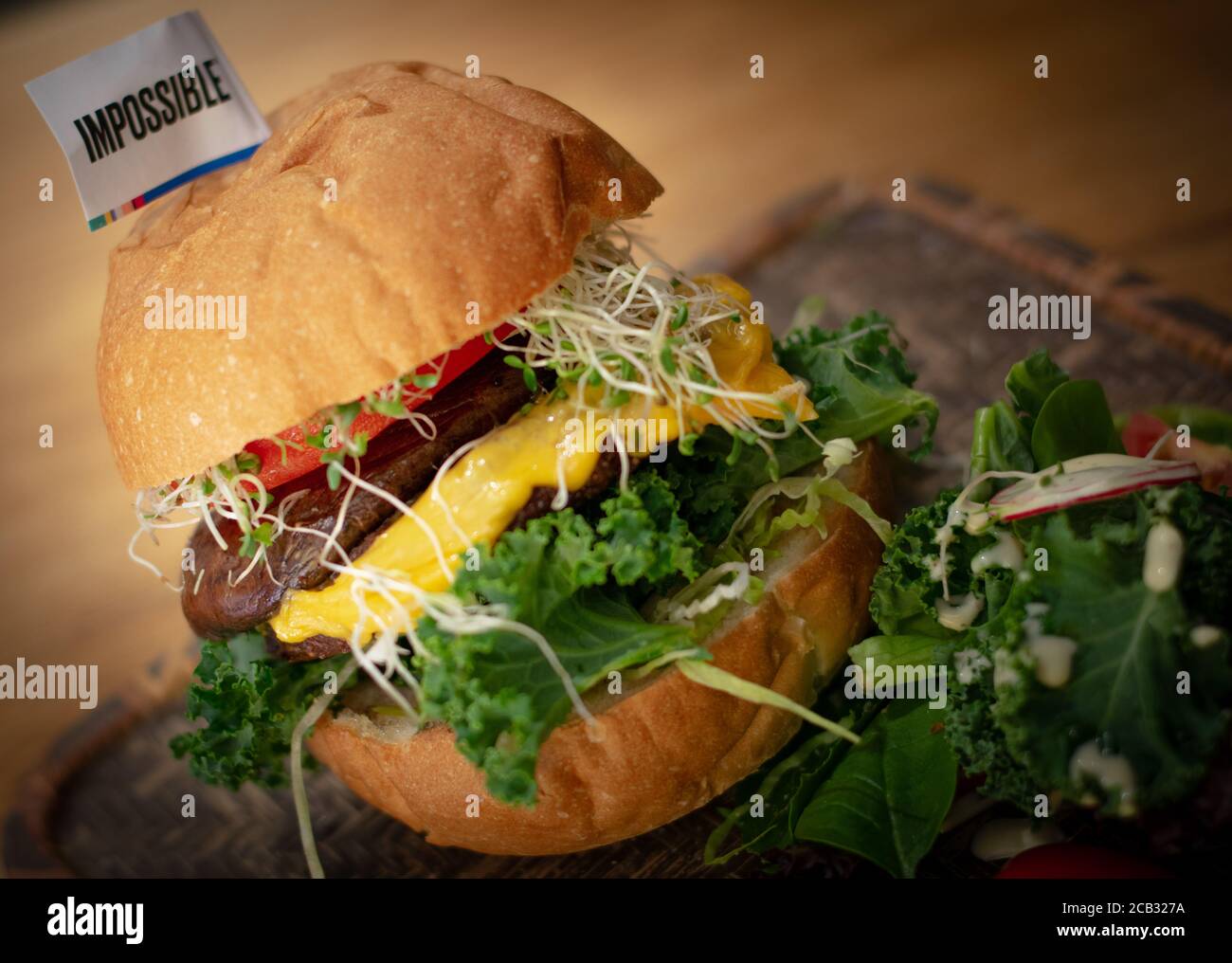 Gros plan d'un hamburger de bœuf de « viande impossible », fait à partir d'ingrédients à base de plantes avec des feuilles de salade et des tomates cerises Banque D'Images