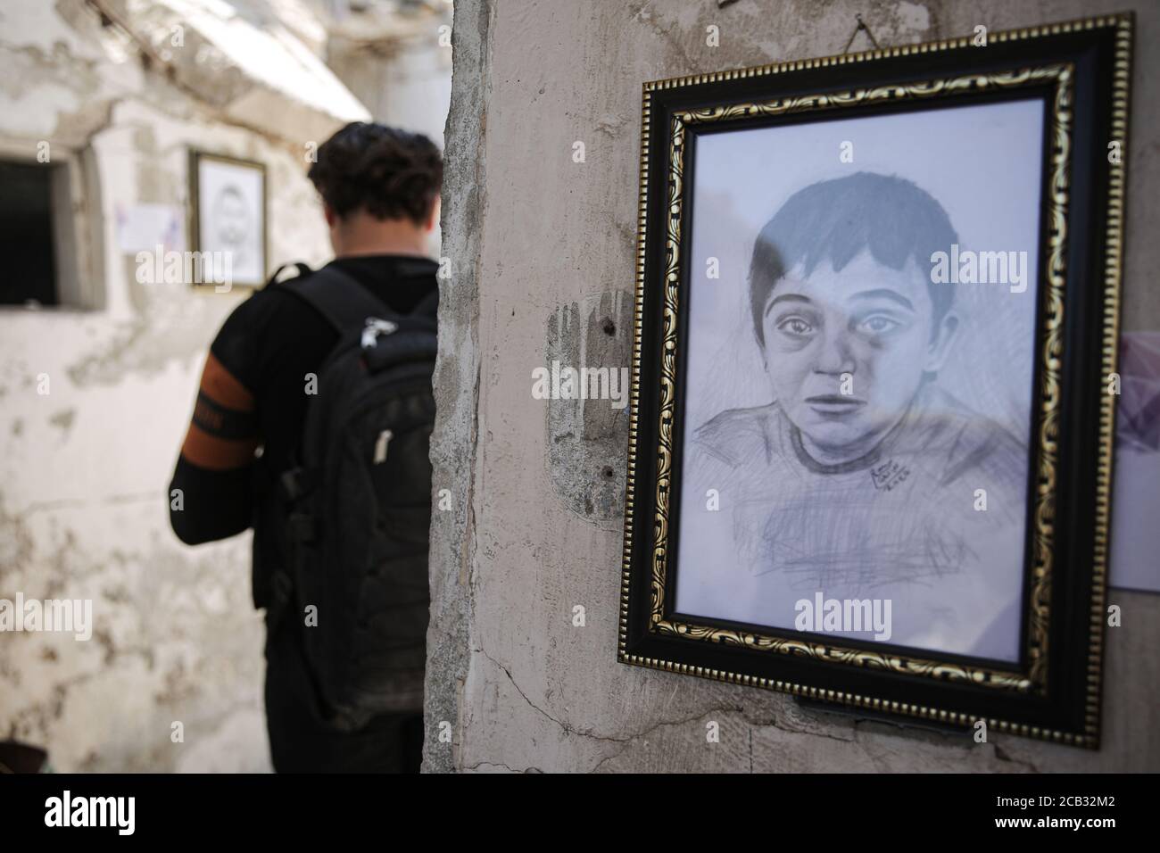 Idlib City, Syrie. 10 août 2020. Un visiteur visite une exposition organisée par l'artiste syrien Rami Abd al-Haq dans l'une des maisons endommagées d'Idlib. Les dessins sont des personnages et des figures qui ont émergé pendant la guerre civile syrienne et ont eu une influence sur les médias. Credit: Aras Alkharboutli/dpa/Alamy Live News Banque D'Images