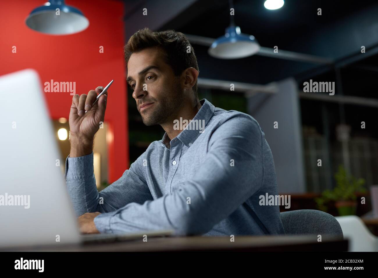 Jeune homme d'affaires concentré travaillant à son bureau après les heures d'ouverture Banque D'Images