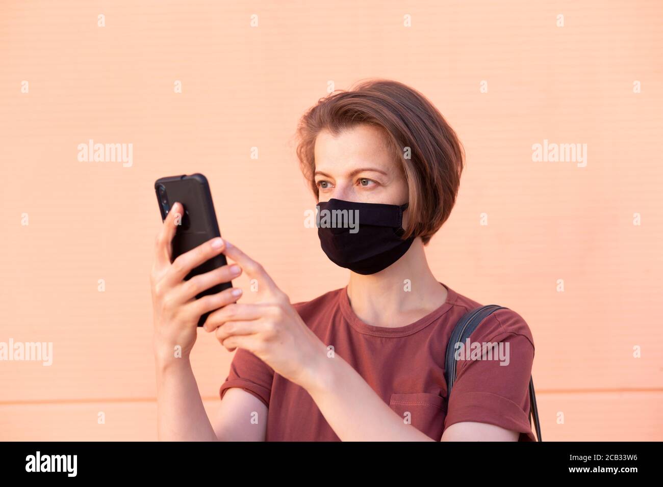 Portrait d'une femme dans un masque médical tenant un téléphone. Banque D'Images