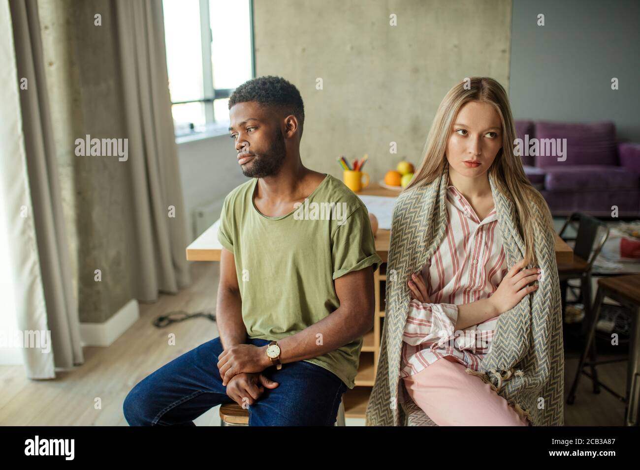 Jeune couple interracial malheureux ayant des problèmes dans la relation, assis dans la salle de séjour à la maison Banque D'Images