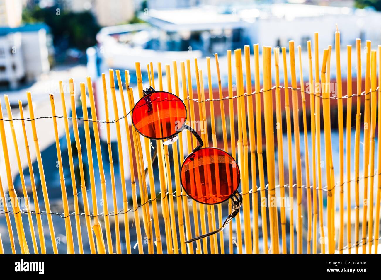 Rouge objectif rond steampunk design sulunettes en journée ensoleillée accroché à une clôture en bambou. Mise au point sélective Banque D'Images