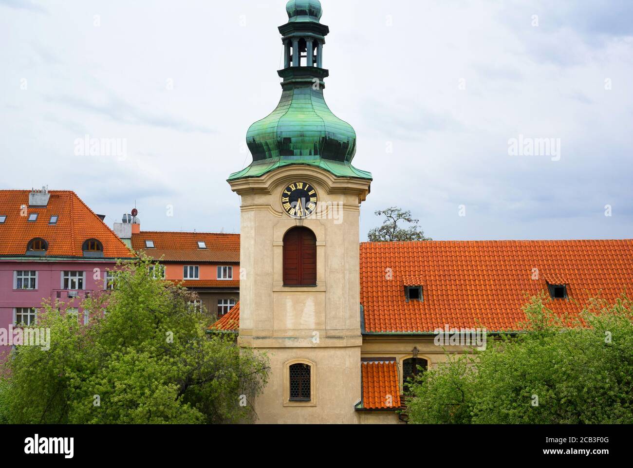 Eglise saint Nicolas, Prague, Vrsovice - Eglise de style baroque. Le bâtiment sacré a une coupole en cuivre vert. Maisons et maisons en rangée avec toit rouge Banque D'Images