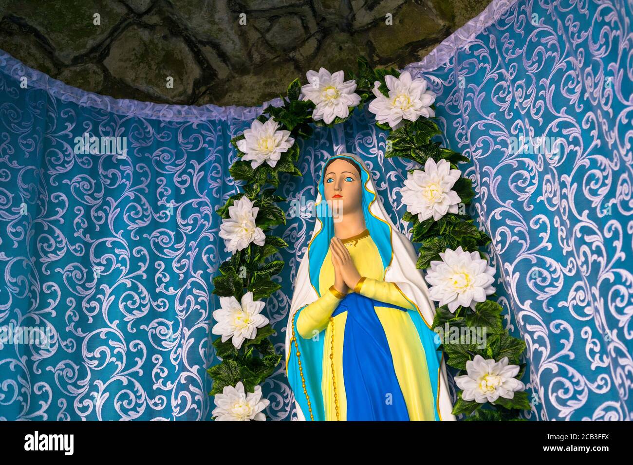 Sanctuaire de la Vierge Marie. La statue de la personne biblique prie. Le rideau bleu est derrière la sculpture. Banque D'Images