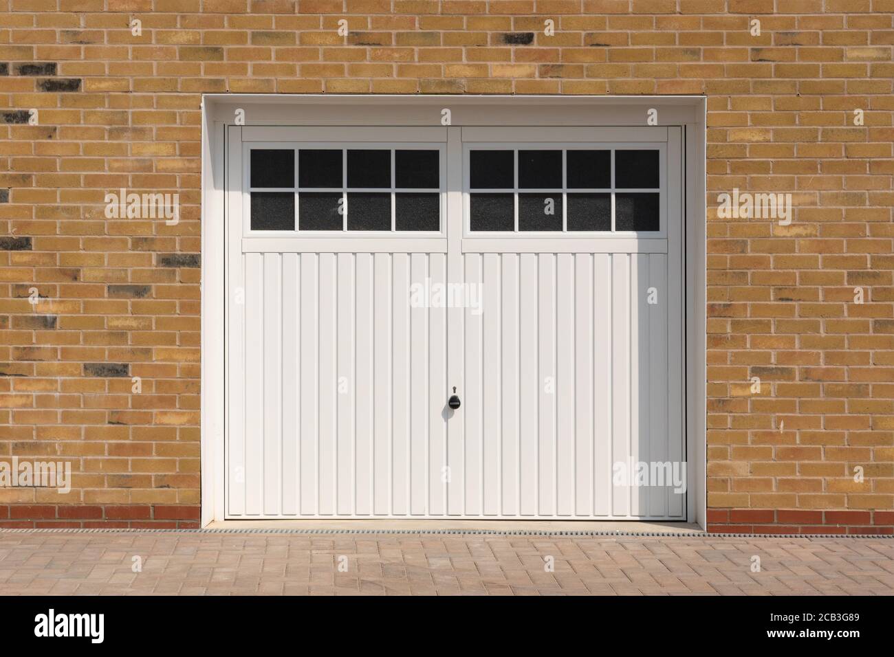 Look classique, portes de garage à charnières blanches, sur une maison récemment construite. Hertfordshire. ROYAUME-UNI Banque D'Images