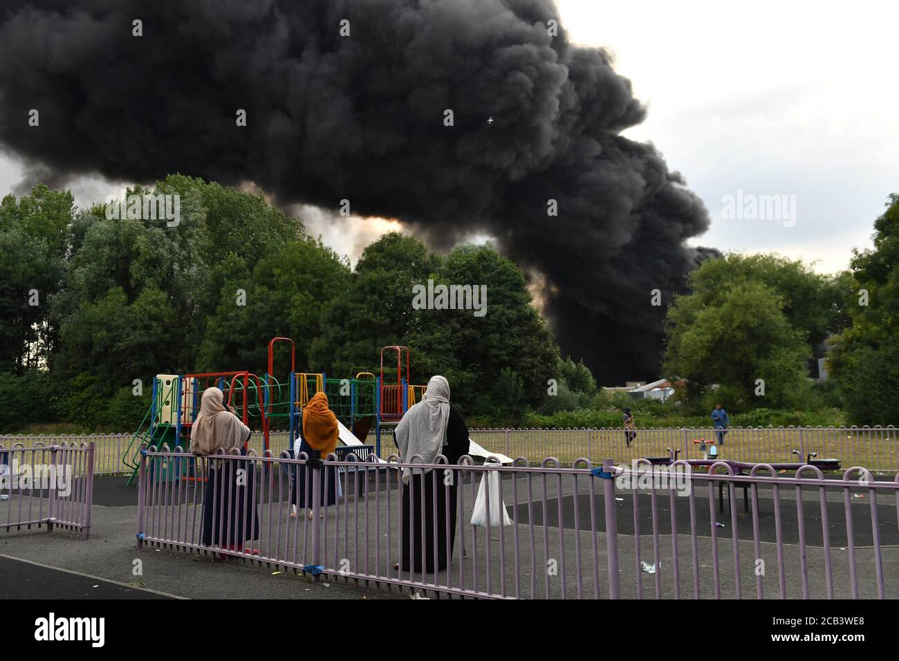Les gens observent les feux de fumée qui s'enveniment d'un incendie violent dans une zone industrielle de Birmingham, tandis que les équipages de 10 pompiers s'attaquent à l'incendie. Banque D'Images