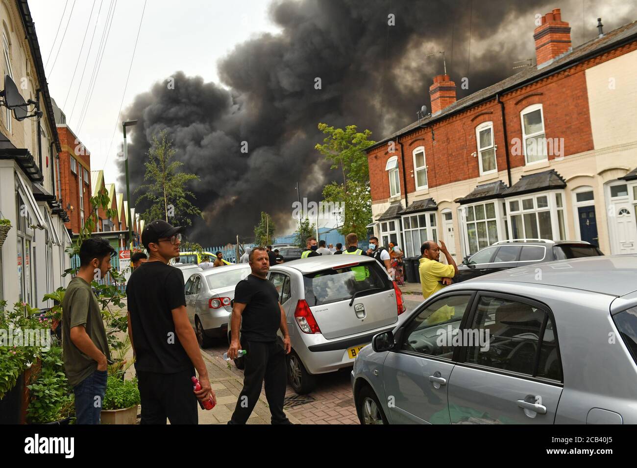 Les habitants de la région observent le fait que de la fumée s'échappe d'un incendie violent dans une zone industrielle de Birmingham. Les équipes de 10 moteurs d'incendie s'attaquent à l'incendie. Banque D'Images