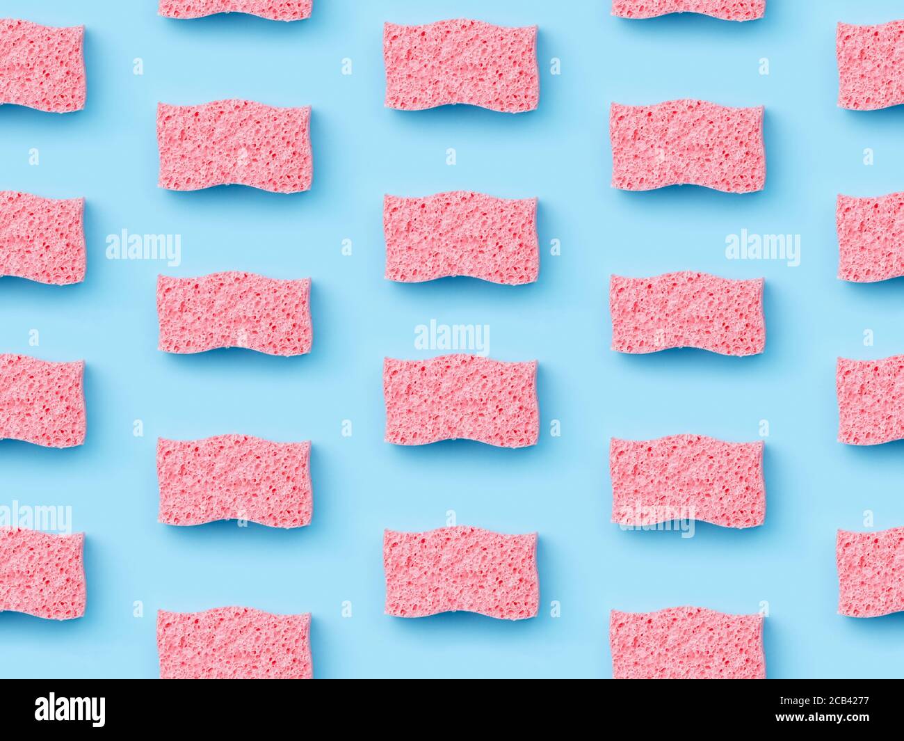 Disposition créative avec éponges pour le lavage de la vaisselle sur fond bleu Banque D'Images