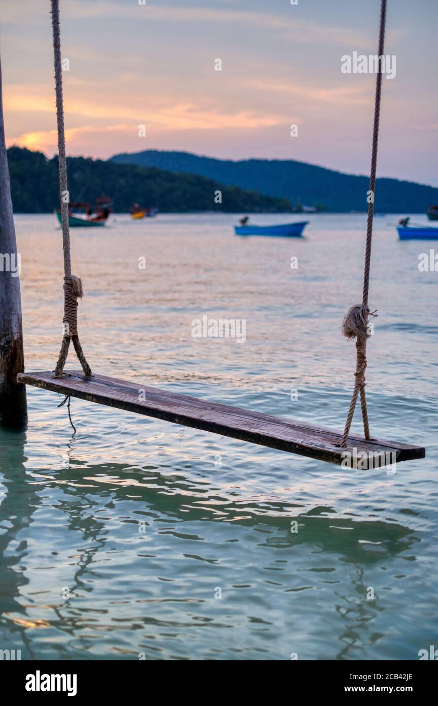 Faites un swing sur la plage de Koh Rong Samloem, Leng Meng Beach (baie de Saracen). Coucher du soleil, bateaux et collines en arrière-plan. Banque D'Images