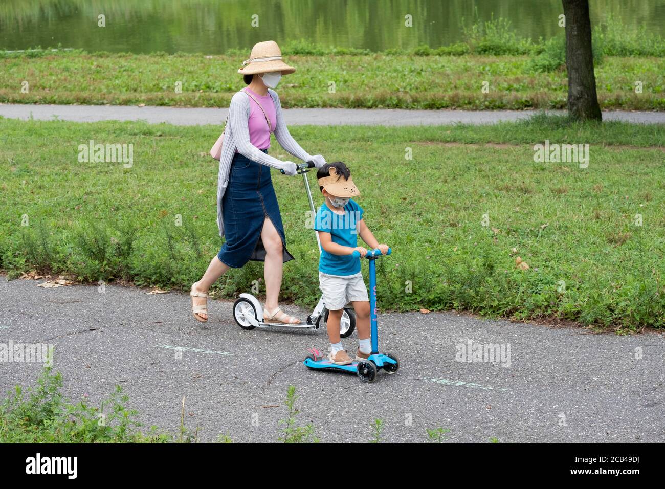 Une mère et un fils d'Amérique asiatique sont en scooter tout en portant un masque chirurgical. À Queens, New York. Banque D'Images