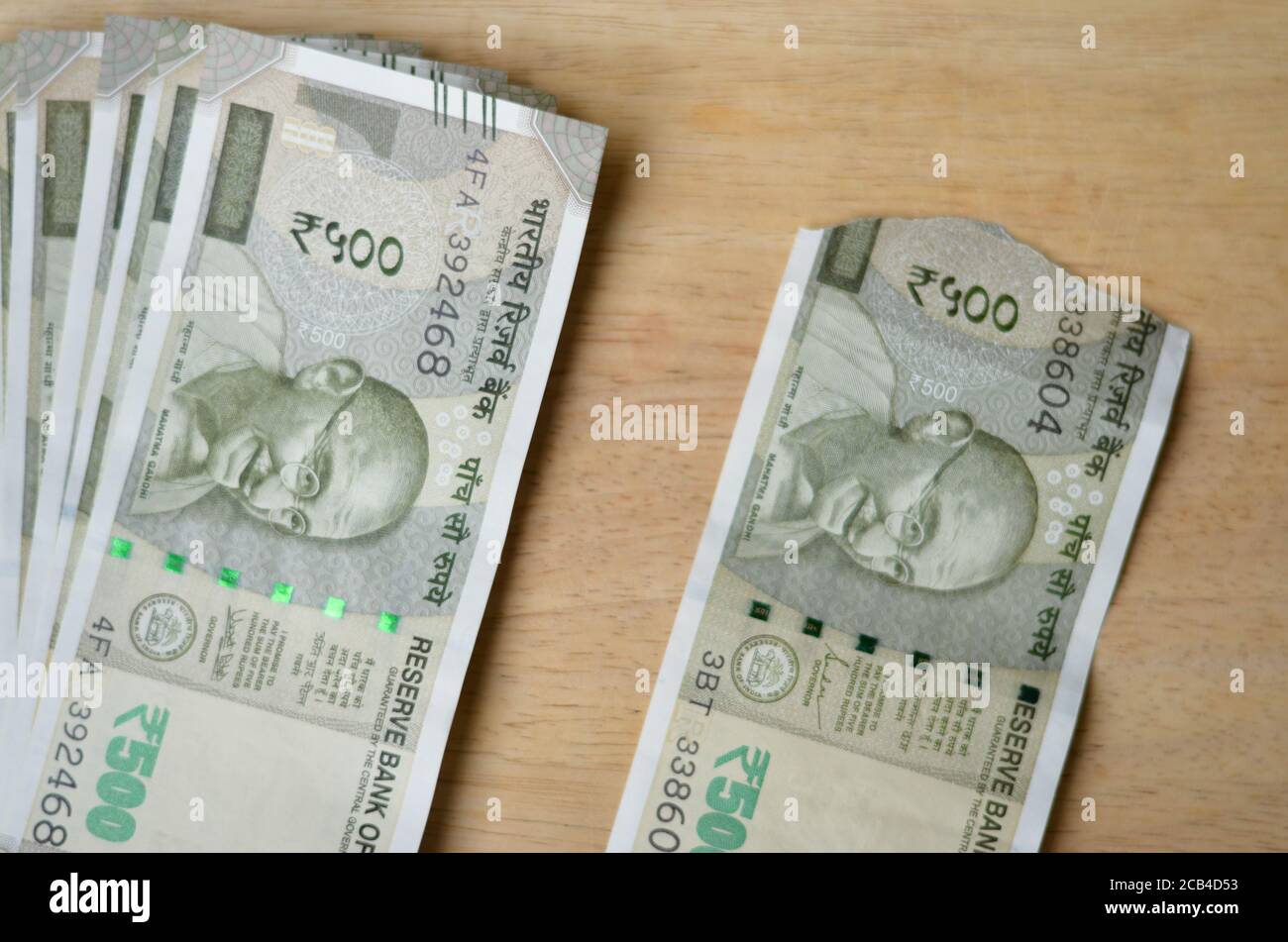 Une nouvelle RS 500 roupies de monnaie indienne notes gardées à côté d'un croquant sur un fond de bokeh en bois. Banque D'Images