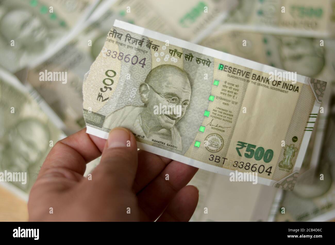 Une main de femme tenant une nouvelle roupie RS 500 déchirée Billets en monnaie indienne montrant Mahatma Gandhi imprimés sur la note sur un arrière-plan bokeh avec beaucoup de Banque D'Images