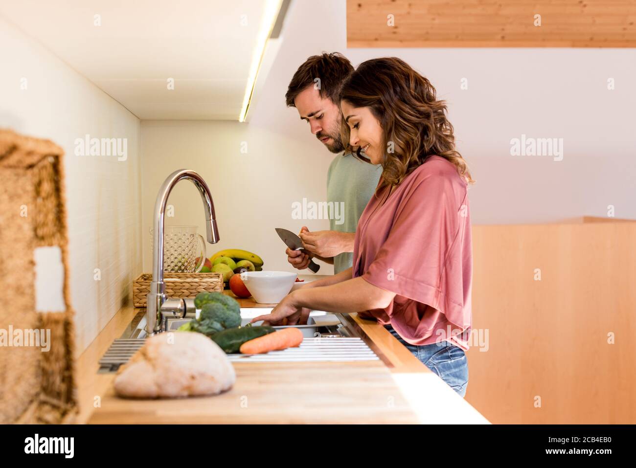 Un jeune couple se rafraîchit tout en préparant le déjeuner Banque D'Images