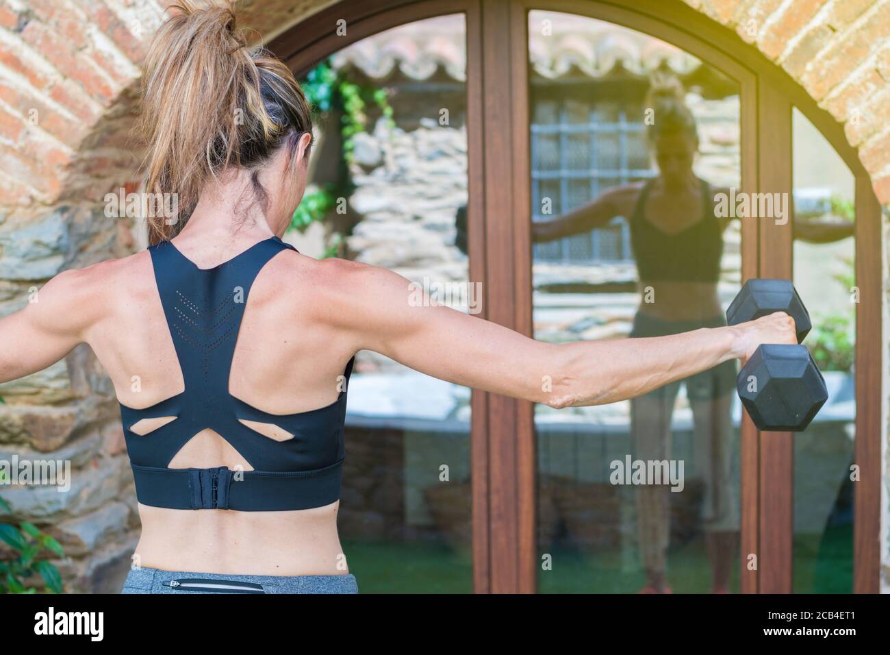 jeune fille blonde avec vitiligo faisant du sport avec des haltères dans avant d'un rétroviseur Banque D'Images