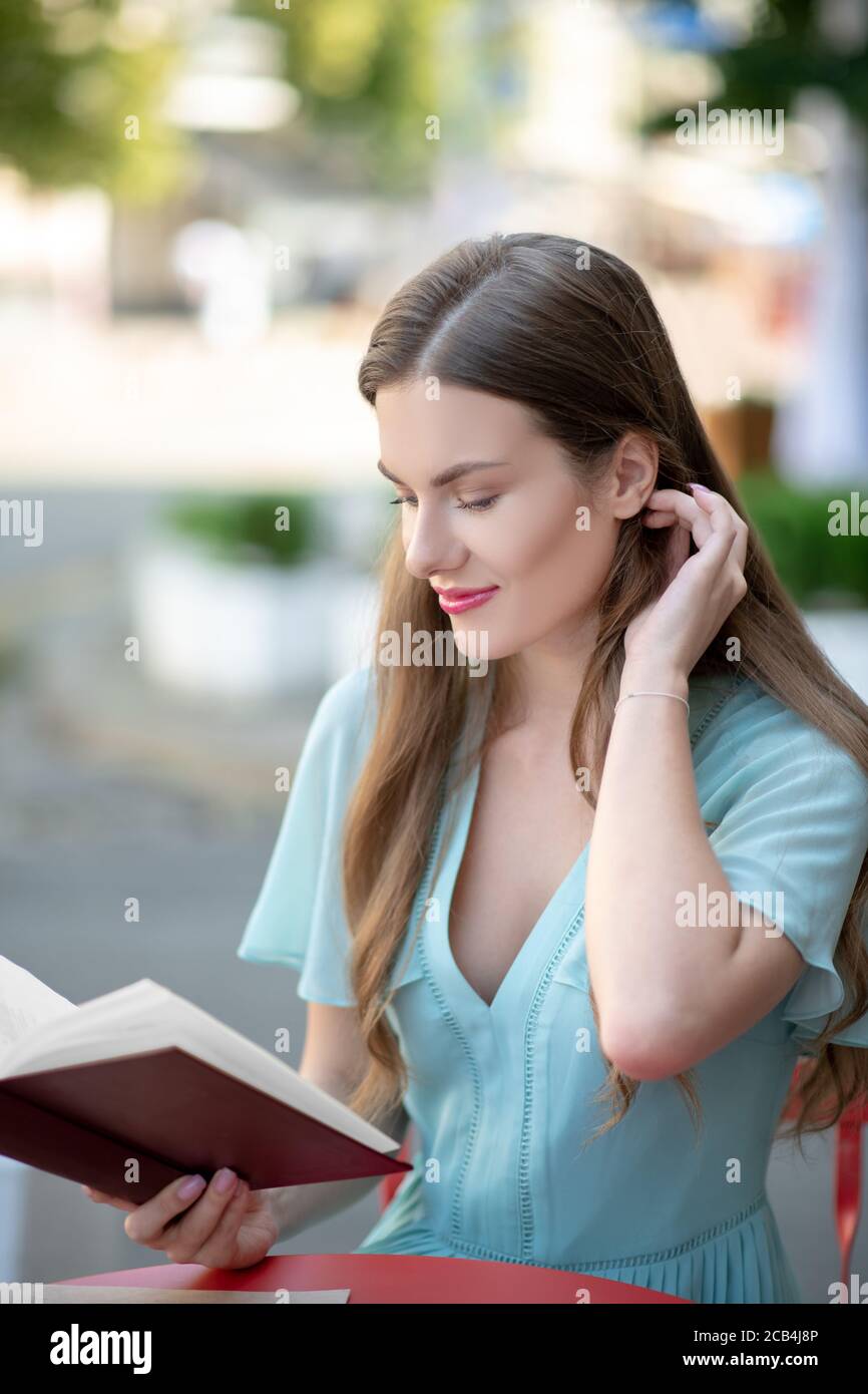 Charmante femme aux cheveux bruns, livre de lecture, elle se chargea des cheveux Banque D'Images