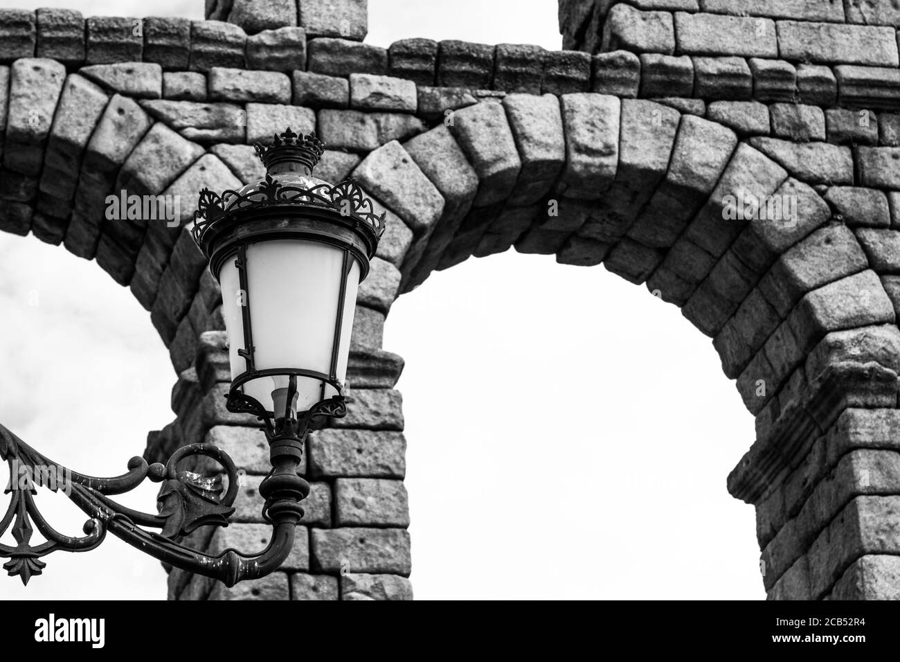 Prise de vue en niveaux de gris à faible angle d'une lampe de rue à proximité d'un ancien pont en pierre Banque D'Images